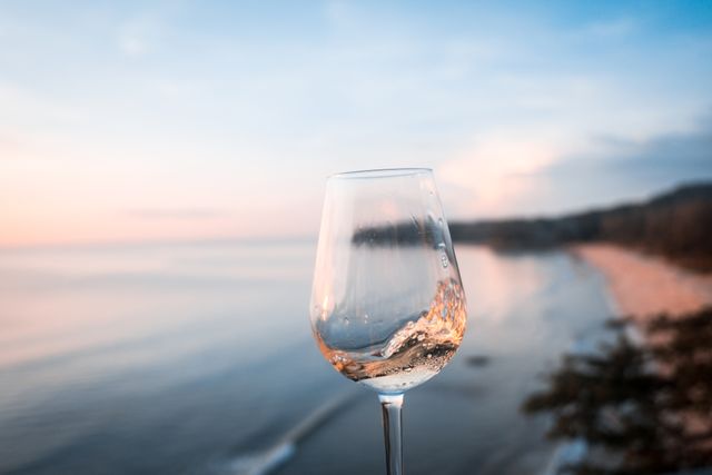 A glass of wine in front of a beach.