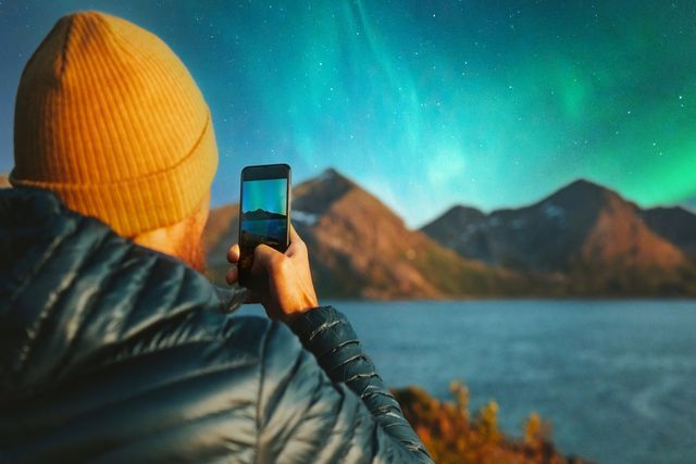 Person using their phone to photograph the Northern Lights
