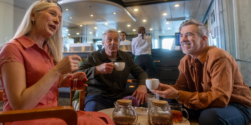 Three people sitting at a table enjoying tea