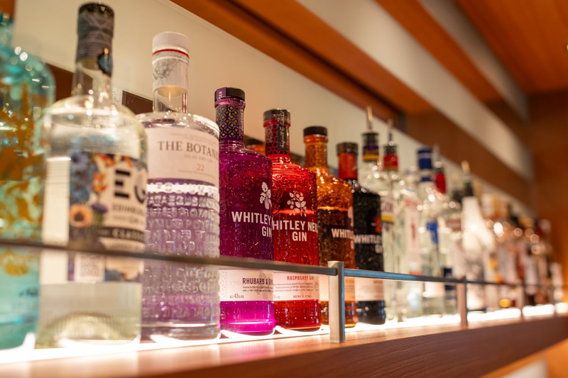 A shelf displaying various liquor bottles, including gin and other spirits