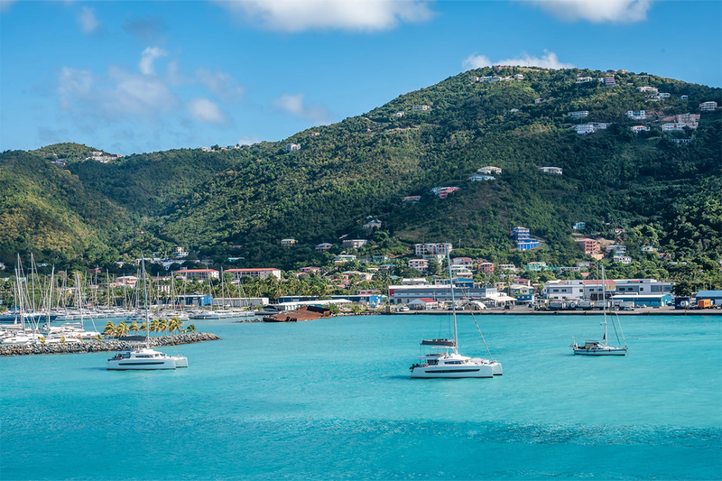 Boats sail on turquoise water near a harbor in Road Town, Tortola