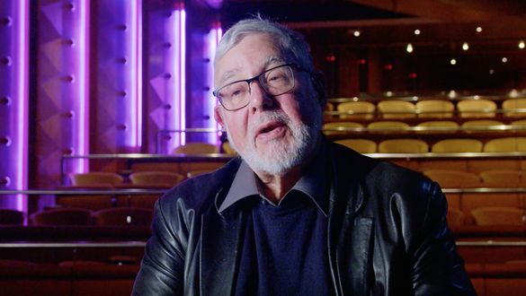 Thomas sits in a theater with purple lights