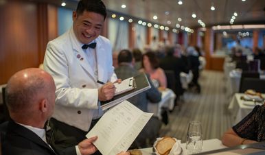 A waiter takes an order from a seated man in Buckingham restaurant on Ambition