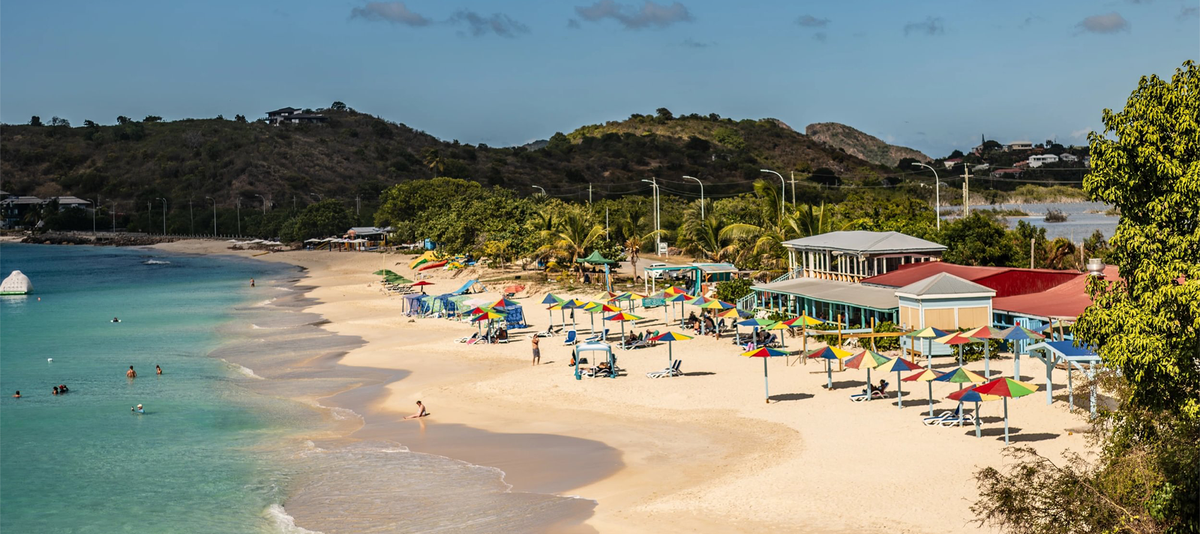 Sandy beach in St Johns Antigua with colorful umbrellas and people relaxing