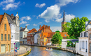 Bruges cityscape, Sint Annarei water canal with tourists boat, medieval houses on embankment in Brugge old town quarter, Bruges city historical center, Saint Anna catholic Church tower spire, Belgium