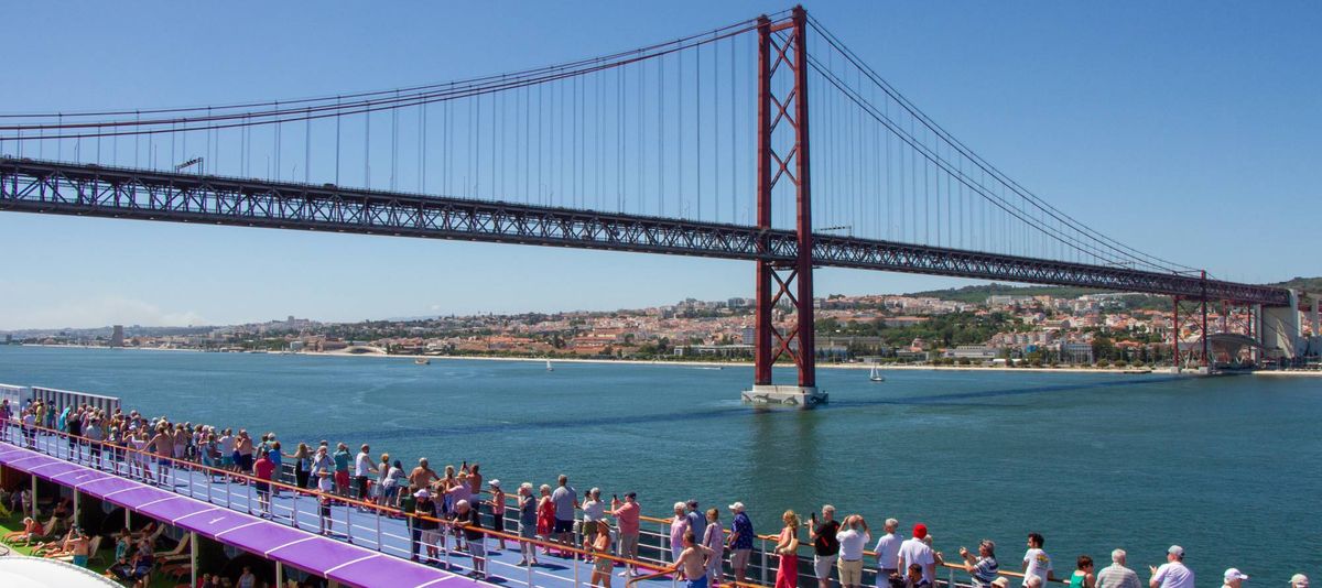 A busy top deck on Ambition cruise ship whilst sailing out of Lisbon under the bridge