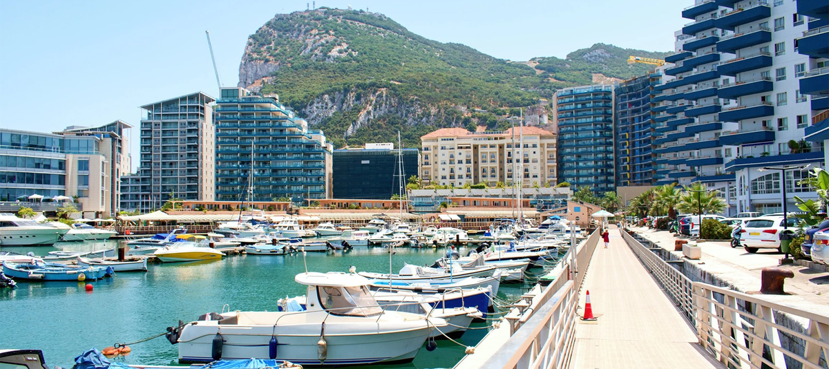 A view of a harbor filled with luxury ships under the Gibraltar Mountain.