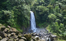 A waterfall cascading down a cliff in Roseau, Dominica surrounded by a forest