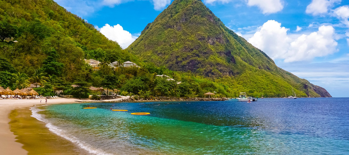 A beach with clear blue water and a mountain in the background