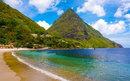 A beach with clear blue water and a mountain in the background