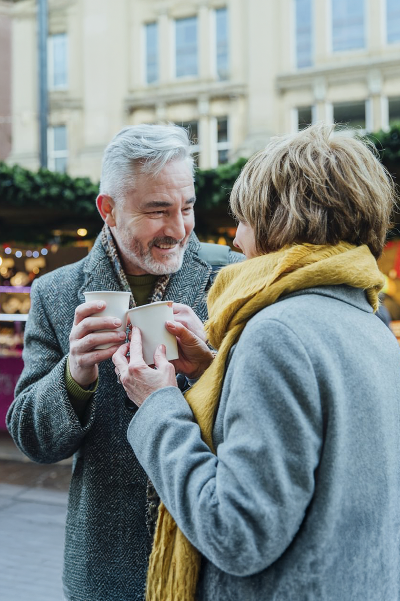 A couple in coats smiling at each other.